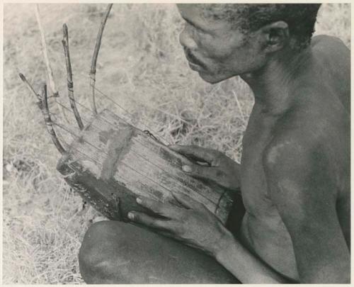 "/Gao Music" playing the //guashi, showing thumbs on strings (print is a cropped image)