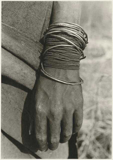 Person's hand showing wire and fiber cord bracelets (print is a cropped image)