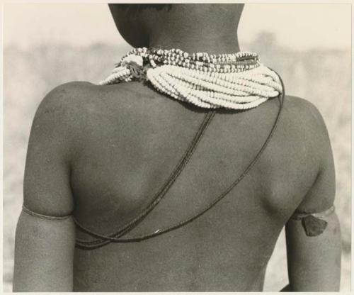 Gaishay, son of "Gao Medicine," wearing necklace and strands of vegetable fiber cord, seen from the back (print is a cropped image)