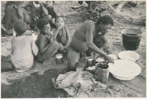 "Old Gau" distributing cooked mealies and a group of children, including !Naishi and "Little ≠Gao" (son of "/Qui Navel" and //Kushay), sitting behind him (print is a cropped image)