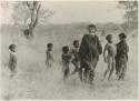 Girls and other children standing in the grass (print is a cropped image)