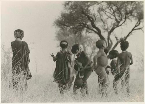 Boys dancing and girls clapping, seen from the back (print is a cropped image)