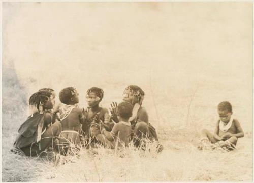 Girls clapping and singing in a circle and a boy sitting apart (print is a cropped image)