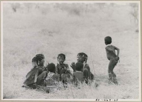 Girls clapping and singing in a circle and a boy dancing (print is a cropped image)