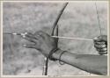 Close-up of "Crooked /Qui's" hands, showing arrow release and position of left hand on bow (print is a cropped image)