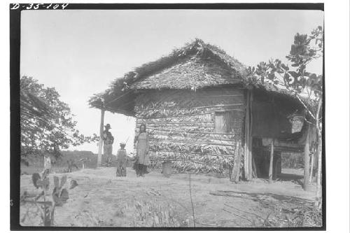 Family in front of house with thatched walls