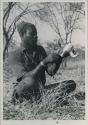 Bela cleaning wart-hog tusks, wearing turban and shirt



