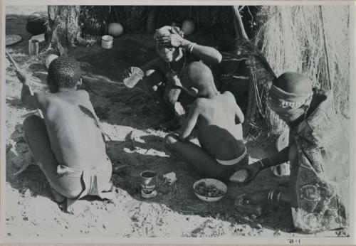 Four people sitting around a fire, seen from behind


