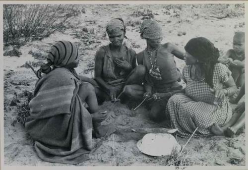 Group of women sitting and playing the dandiri

