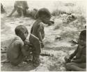 "Children playing curing dance": /Gaishay putting dance rattles on his younger brother, Debe, Bau sitting to the right, and unidentified people in the background (print is a cropped image)