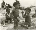 "Children playing curing dance": /Gaishay watching Debe dance while wearing rattles; Bau singing and clapping with unidentified people in the background (print is a cropped image)