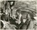 "Toys, Gun, Tsamgao's camera": Gao, father of N!aba, an unidentified child, and a bucket (print is a cropped image)