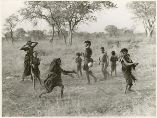 "Women's Ball Game": Girls playing N!owa t/ama (melon tossing game) / tamah n!o’an (ball game); other children present in the background (print is a cropped image)