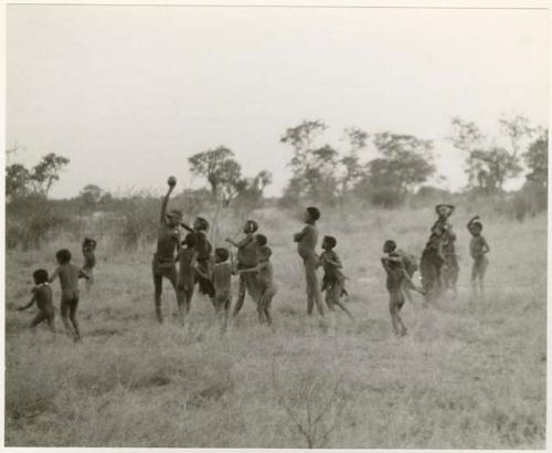 "Women's Ball Game": Group of youths; a boy is holding aloft the melon with which girls were playing N!owa t/ama (melon tossing game) / tamah n!o’an (ball game) (print is a cropped image)