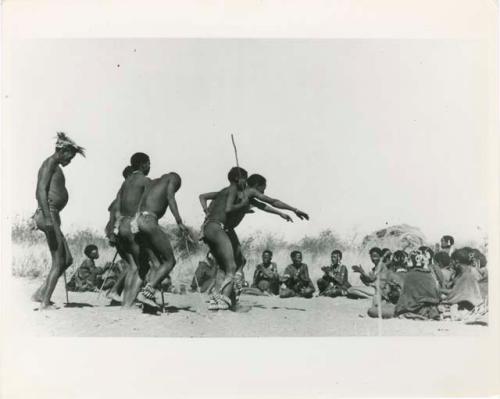 "Daytime Dance at Gautscha 1952, Early in the Dance, approach": Men dancing through a circle of women sitting, with one man's arms outstretched (print is a cropped image)