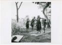 "The 1957-8 Games": Group of women and girls playing Tcxai Djxani (a dancing game), dancing in a line, with N!ai at the end of the line, clapping (print is a cropped image)