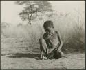 "Auto": Boy sitting and playing with a toy car made from veldkos (print is a cropped image)