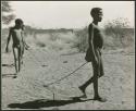 "Auto": Boys pulling toy cars made from veldkos with sticks (print is a cropped image)