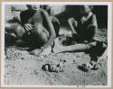 "Auto": Group of children sitting in front of a skerm, with toy cars made of veldkos on the ground next to them, close-up (print is a cropped image)