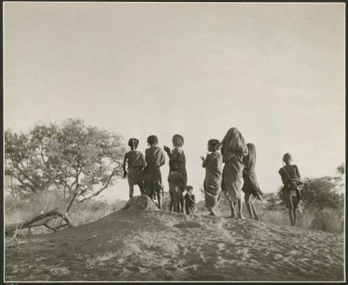 "N!ai on ant hill making patterns, girls playing on ant hill": Children dancing on an ant hill (print is a cropped image)