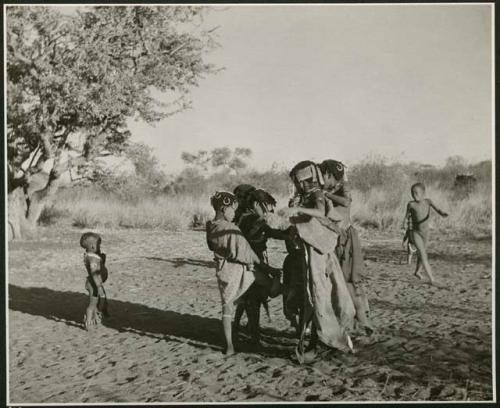 "N≠a N≠a Hau": Girls playing N≠a N≠a Hau / N!hau-N!hau (the basket game), weaving their feet together and hopping around in a circle on one foot, singing (print is a cropped image)