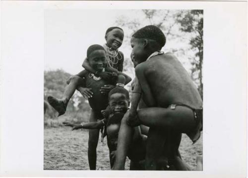 "Boys' play": Group of boys playing piggy-back (print is a cropped image)