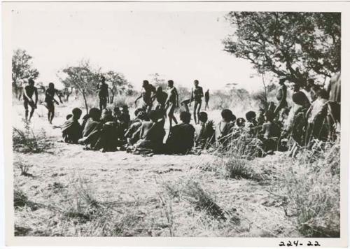 "Children": Boys and other men approaching, dancing at the beginning of a daytime dance, with the circle of women sitting open at the front, "Gao Medicine" dancing with two little boys following him on the right