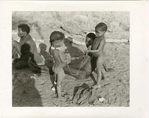 "Photos of Children": !Ungka Norna and Bau playing with string and other unidentified people; part of Elizabeth Marshall Thomas's child study (print is a cropped image)