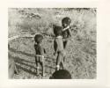 "Photos of Children": !Ungka Norna, Bau and /Gaishay with a string and other unidentified people; part of Elizabeth Marshall Thomas's child study (print is a cropped image)