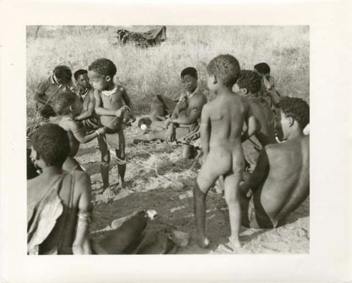 "Photos of Children": !Ungka Norna, Bau and /Gaishay with a string and other unidentified people; part of Elizabeth Marshall Thomas's child study (print is a cropped image)