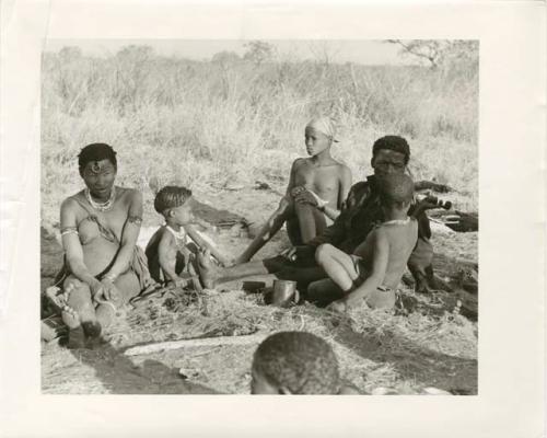 "Photos of Children": !U, !Ungka Norna, ≠Toma, /Gaishay sharing a pipe with an unidentified person, "Gao Lame" wearing a headscarf, and other unidentified people; part of Elizabeth Marshall Thomas's child study (print is a cropped image)