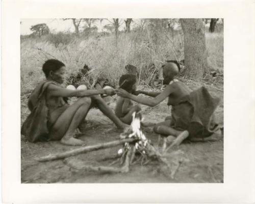 "Photos of Children": /Naoka (!U's mother), !Ungka Norna, and an unidentified, visiting girl beside a fire (print is a cropped image)