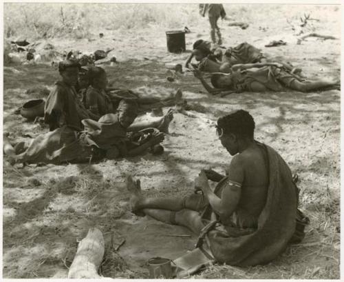 Two groups of women and children lying in the shade; the group in the foreground includes "Old /Gasa," Khuan//a, and other unidentified people, and the second group includes !U next to !Ungka Norna and an unidentified woman, sleeping (print is a cropped image)