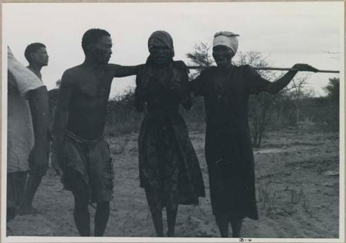 N/kxabe, N//aba, with stick over her shoulder, and /Gaishay standing together



