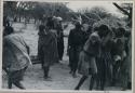 Group of people performing the Eland Dance; group of women clapping; men with wooden horns on their heads




