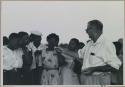 Group of people standing with C.J. Mathias, who is holding something out to a group of women



