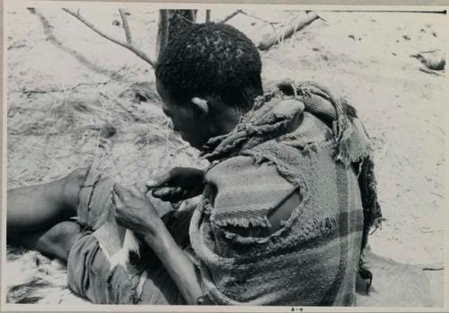 Tama sewing, showing how he makes a hole with an awl for the thread to go through, close-up (copy of color slide 2001.29.8361)




