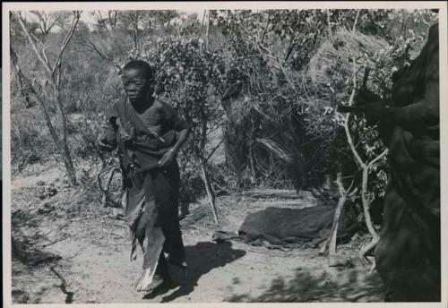 [No folder title]: Woman walking, person holding two sticks to the side