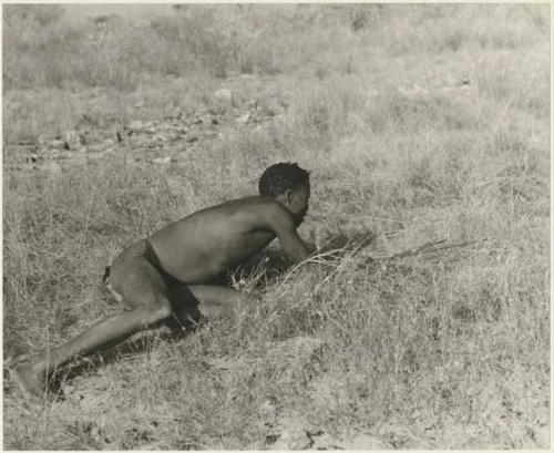 "Crooked /Qui" crawling in grass, holding bow and arrow (print is a cropped image)