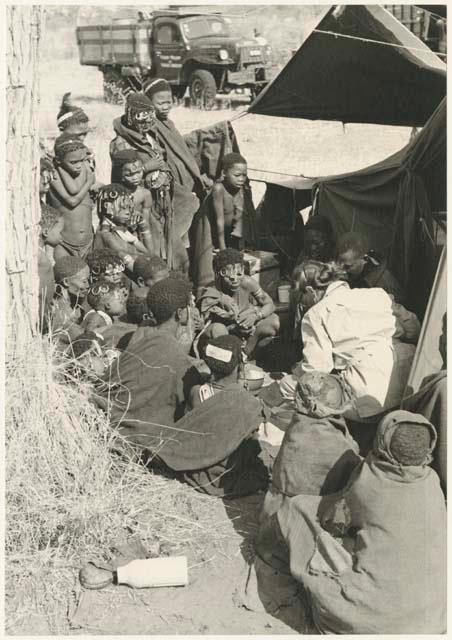 Group of Ju/'hoansi, Kernel Ledimo, and Lorna Marshall gathered around to look at beads (print is a cropped image)