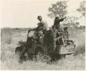 Expedition members and Ju/'hoansi riding on a Jeep (print is a cropped image)