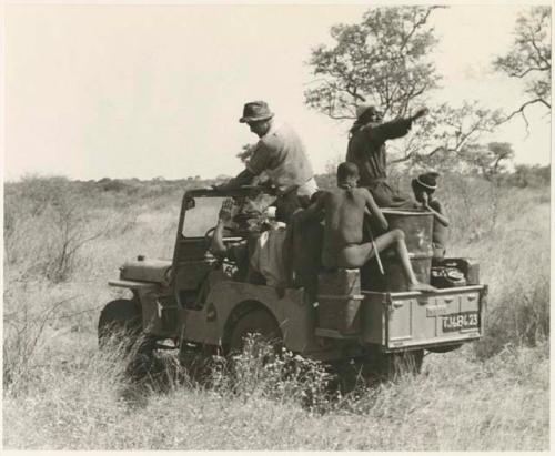 Expedition members and Ju/'hoansi riding on a Jeep (print is a cropped image)