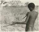 !Naishi (brother of /Goishay) playing a musical bow, seen from behind (print is a cropped image)