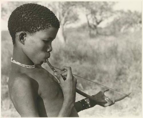 !Naishi (brother of /Goishay) in profile, playing a musical bow (print is a cropped image)