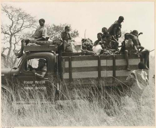 Truck loaded with a group of Ju/'hoansi on top, with Heinrich Neumann behind the wheel (print is a cropped image)