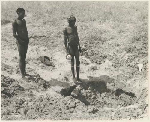 "Crooked /Qui" and "/Gao Music" standing by a waterhole (print is a cropped image)