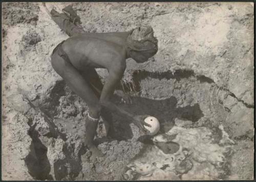 "/Gao Music" dipping an ostrich eggshell in a waterhole (print is a cropped image)