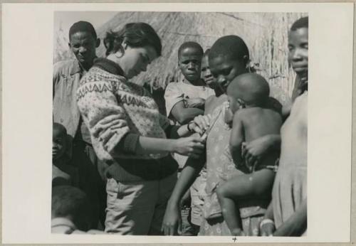 Woman holding a baby and having her skin color documented by Deborah Marshall (print is a cropped image)