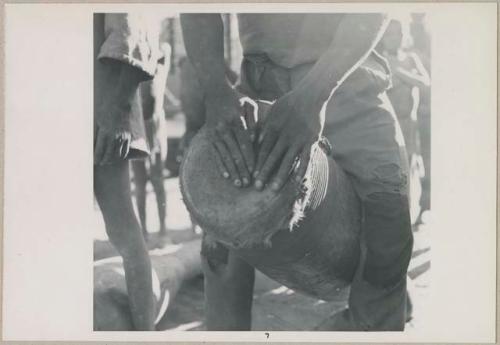 Man playing a drum, close-up of his hands (print is a cropped image)