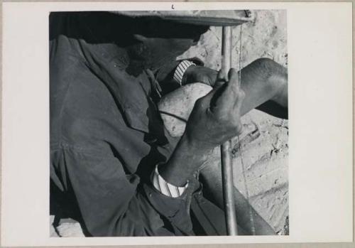 Kafuro playing the hunting bow, braced, with calabash, view over his right shoulder (print is a cropped image)